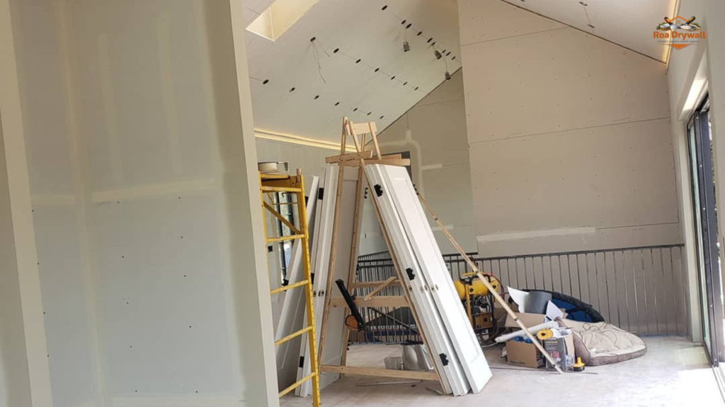 Professional drywall installation in progress with workers hanging drywall panels and finishing interior walls for a residential construction project.